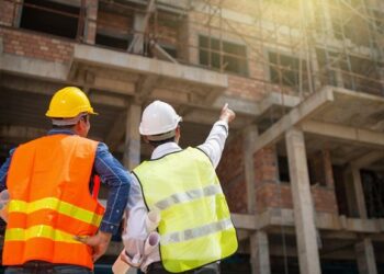 Construction engineers discussion with architects at construction site or building site of highrise building