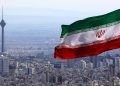 Iran's national flag waves as Milad telecommunications tower and buildings are seen in Tehran, Iran, Tuesday, March 31, 2020. In recent days, Iran which is battling the worst new coronavirus outbreak in the region, has ordered the closure of nonessential businesses and banned intercity travels aimed at preventing the virus' spread.   (AP Photo/Vahid Salemi)